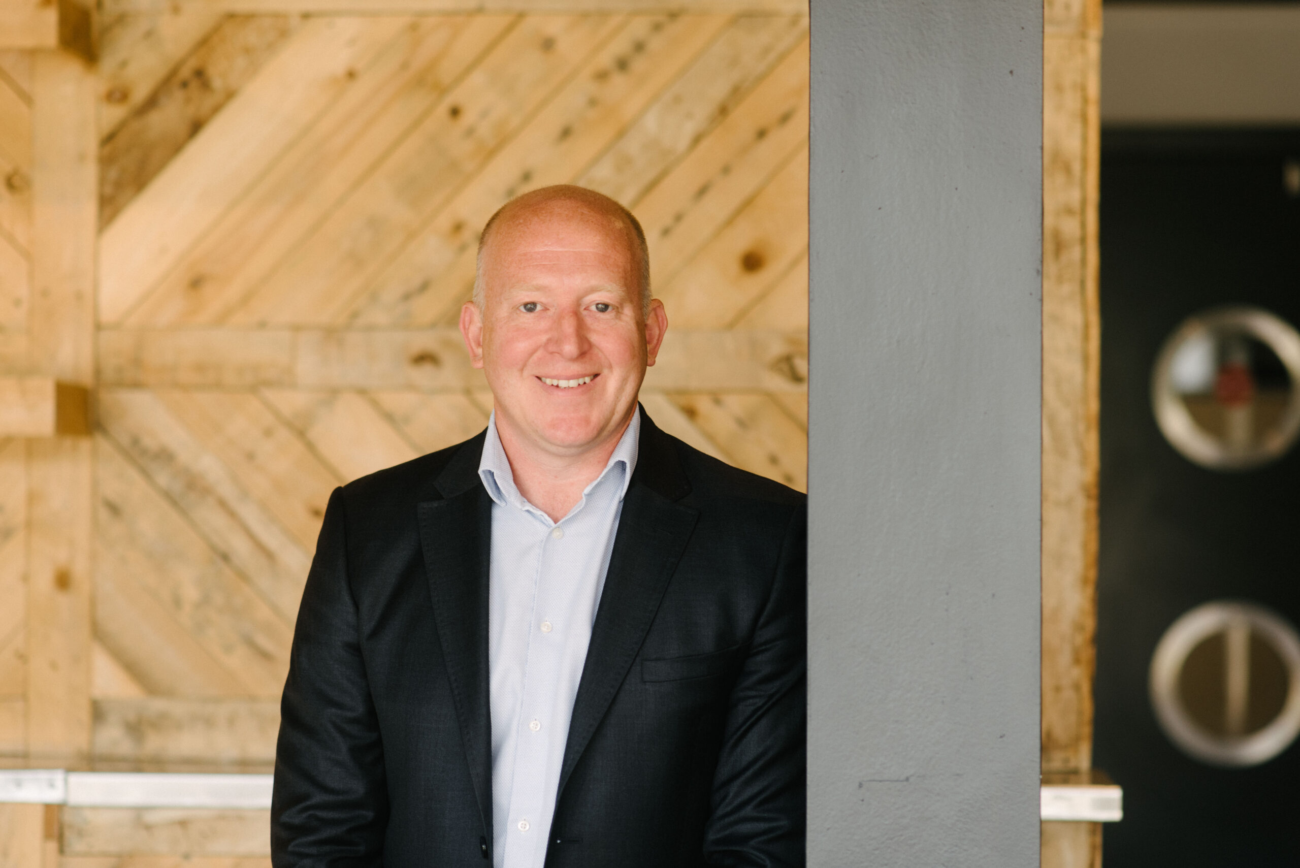 Peter Williams, CEO of Propp, in a black suit standing next to a metal pillar.