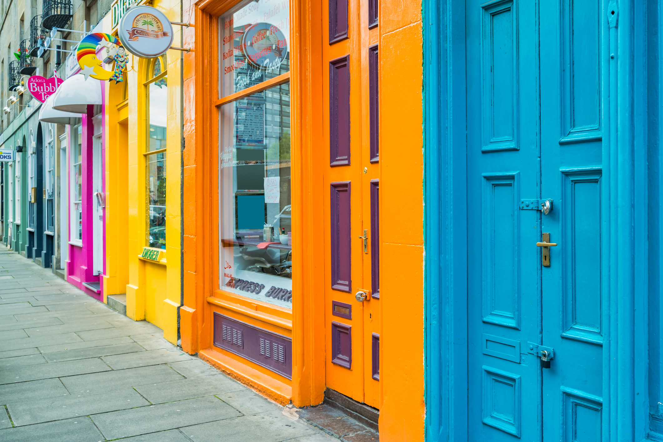 A colourful row of shop fronts in blue, orange and yellow