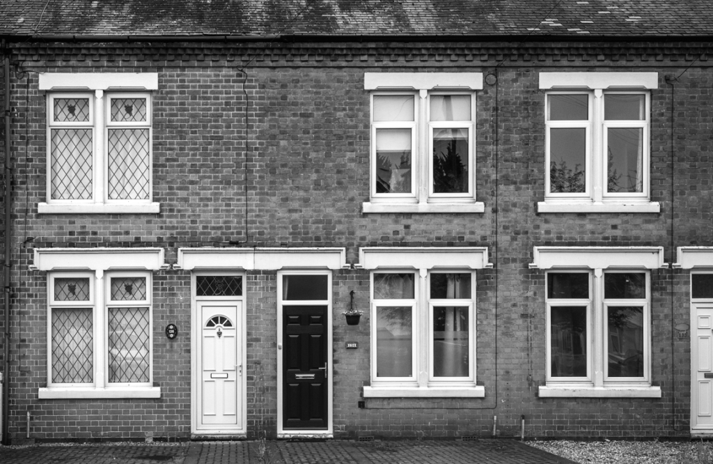 Black and white photo of some classicly British terraced houses from the street view